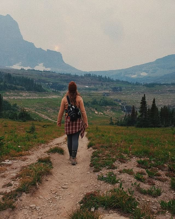 A hiker on a trail with mountains in the background